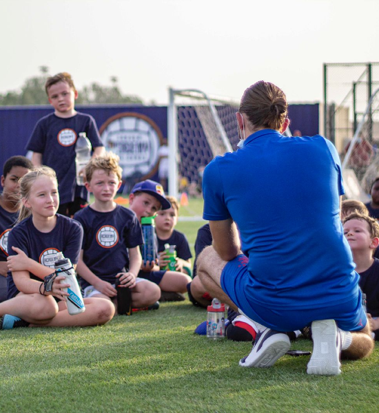 A football coach speaks to a group of young footballers